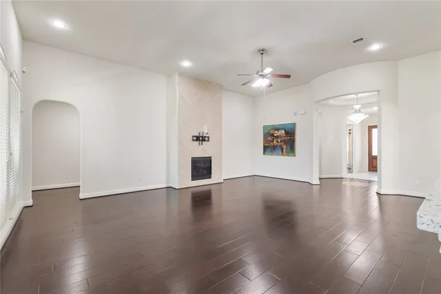 an empty room with wooden floor chandelier and windows