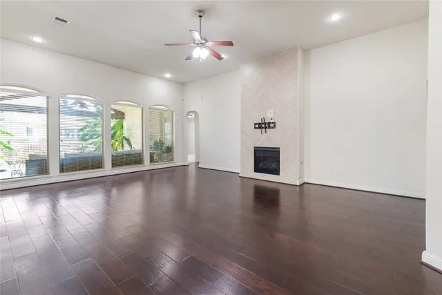 an empty room with wooden floor fan and windows