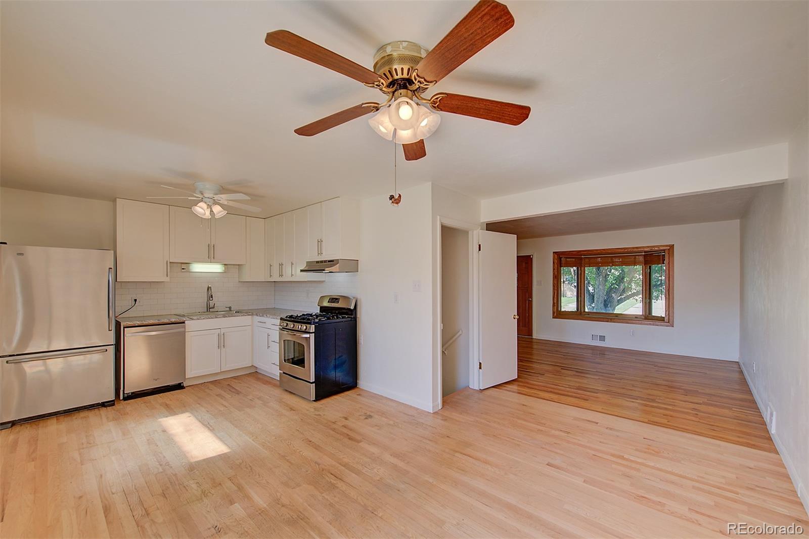 6054 Iris Way Arvada, CO 80004 - Photo 13 of 44 a open kitchen with stainless steel appliances granite countertop a refrigerator a stove a sink dishwasher and a stove with wooden floor