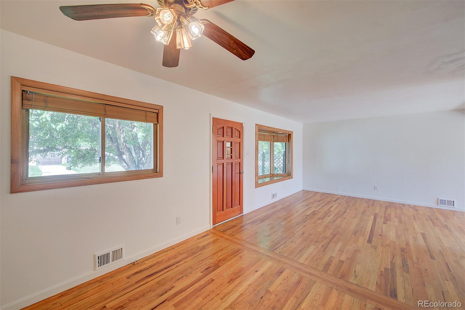 6054 Iris Way Arvada, CO 80004 - Photo 4 of 44 a view of an empty room with window and wooden floor