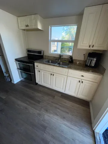 a kitchen with a stove a window and cabinets