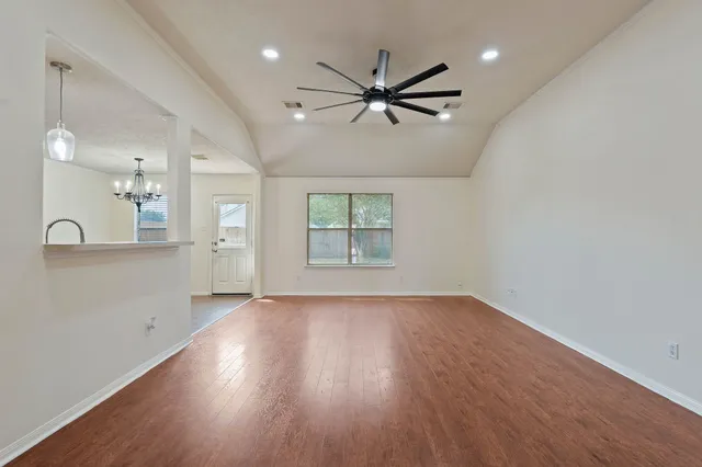 an empty room with wooden floor and windows