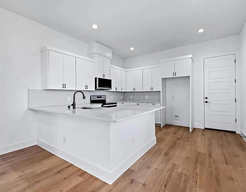 1605 Logan Street Fort Worth, TX 76104 - Photo 7 of 17 a kitchen with stainless steel appliances a sink a stove a refrigerator cabinets and wooden floor