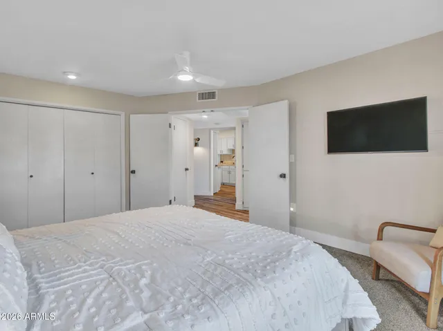 a bedroom with a bed a flat screen tv and a large window