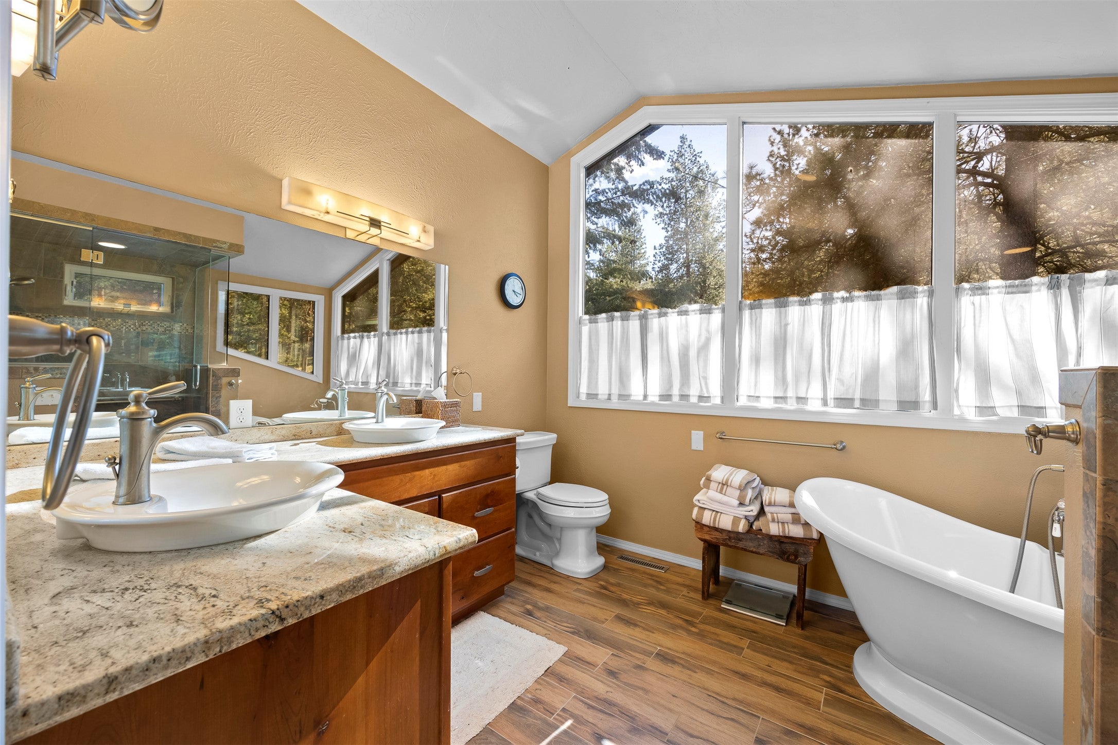730 Big Flat Road Missoula, MT 59804 - Photo 46 of 59 Bathroom featuring a freestanding bath, dark wood-style flooring, double vanity, and lofted ceiling