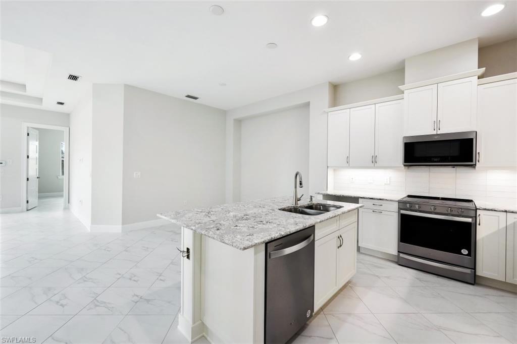 6435 Negril Isle Drive Naples, FL 34113 - Photo 12 of 35 a kitchen with stainless steel appliances granite countertop a stove top oven a sink and a granite counter tops