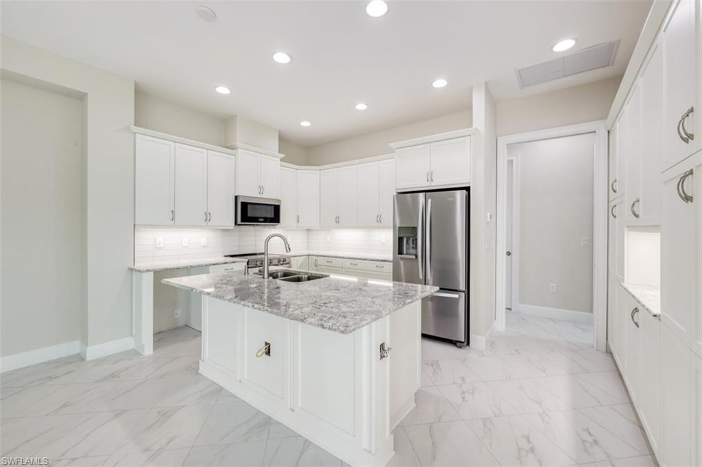 6435 Negril Isle Drive Naples, FL 34113 - Photo 14 of 35 a kitchen with stainless steel appliances granite countertop a refrigerator and a sink