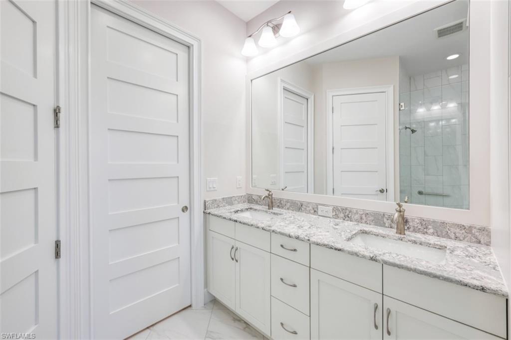 6435 Negril Isle Drive Naples, FL 34113 - Photo 21 of 35 a bathroom with a granite countertop sink and a mirror