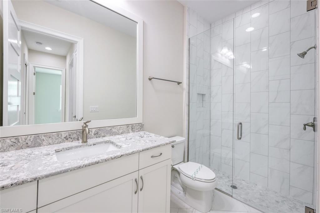 6435 Negril Isle Drive Naples, FL 34113 - Photo 24 of 35 a bathroom with a granite countertop sink toilet and shower