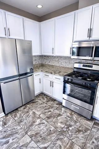 a kitchen with granite countertop a refrigerator sink and cabinets