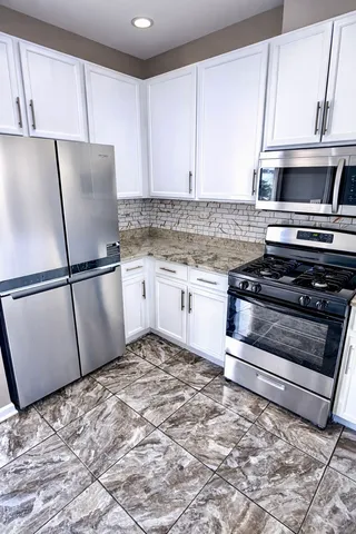 a kitchen with granite countertop a refrigerator sink and cabinets