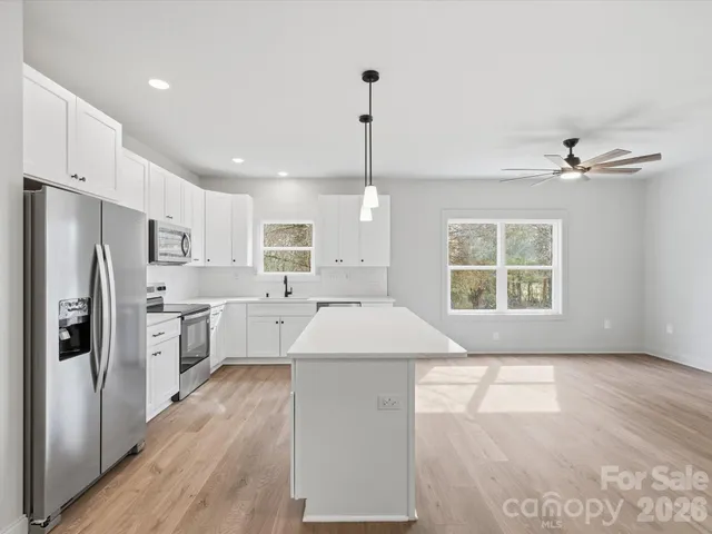 a open kitchen with kitchen island white cabinets and stainless steel appliances