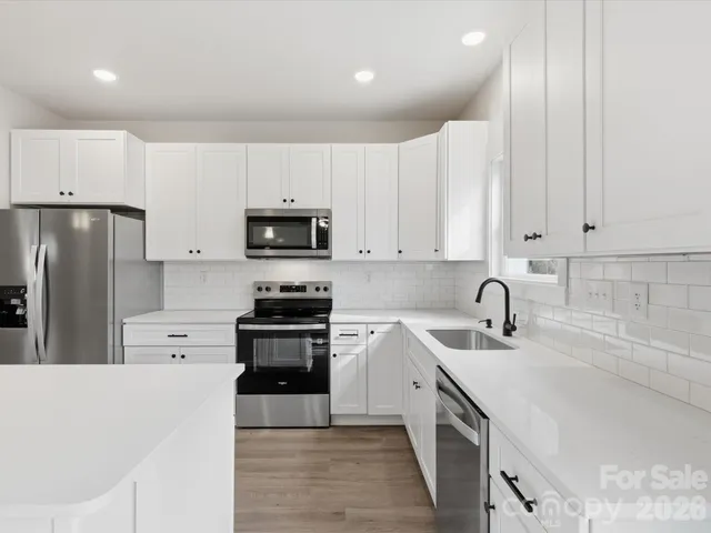a kitchen with white cabinets sink and stainless steel appliances
