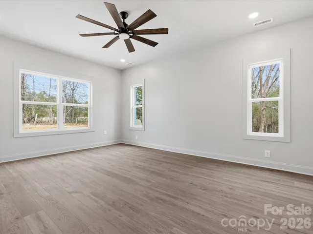 a view of an empty room with window and wooden floor