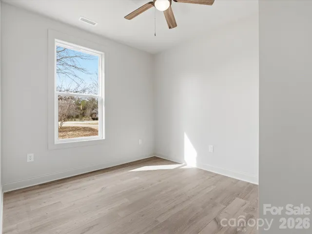 an empty room with a window and a ceiling fan
