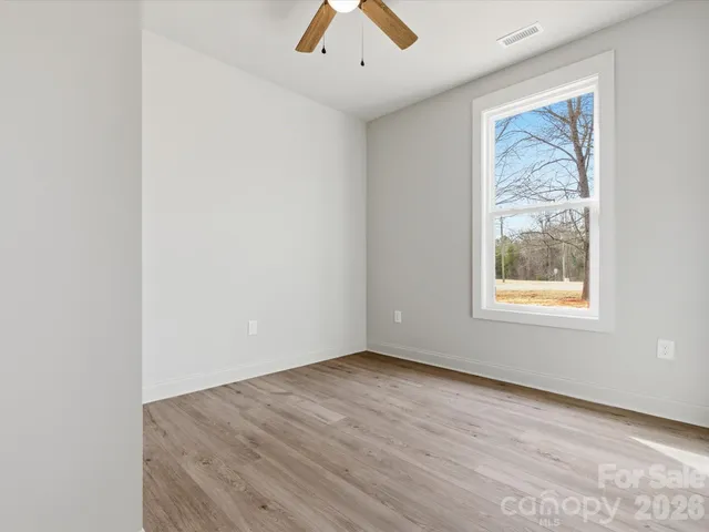 an empty room with a window and a ceiling fan