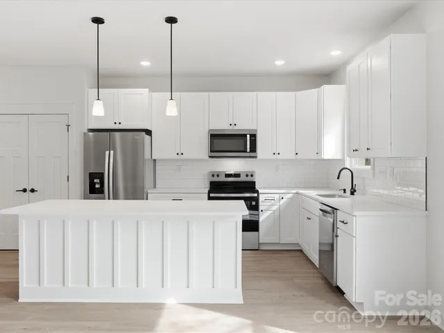 a kitchen with white cabinets and stainless steel appliances
