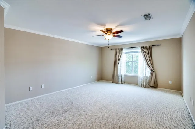 an empty room with windows and chandelier fan