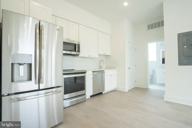 a kitchen with stainless steel appliances white cabinets and a refrigerator