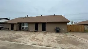 a view of a house with a barbeque and wooden fence