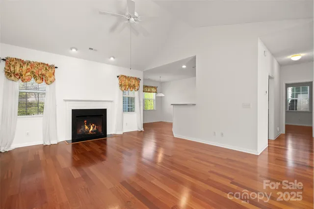 an empty room with wooden floor a fireplace and windows