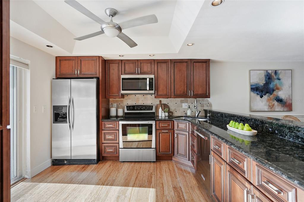 936 Pinellas Bayway South, Unit T5 Tierra Verde, FL 33715 - Photo 13 of 38 a kitchen with kitchen island granite countertop stainless steel appliances and wooden cabinets