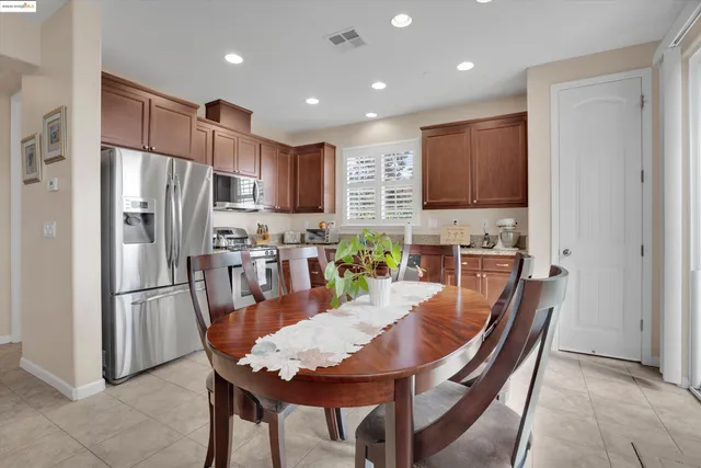 a kitchen with stainless steel appliances granite countertop a refrigerator a stove a sink a dining table and chairs