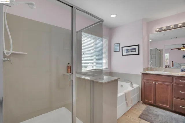 a bathroom with a granite countertop sink a large mirror a bathtub and next to a window