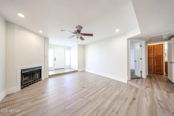 an empty room with wooden floor fireplace and windows
