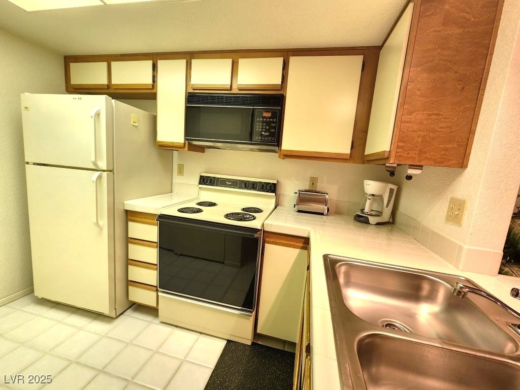 1964 Las Palmas Lane, Unit 141 Laughlin, NV 89029 - Photo 9 of 12 Kitchen featuring a sink, tile countertops, and white appliances