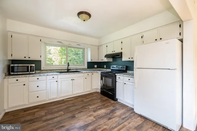 a kitchen with granite countertop white cabinets and white appliances