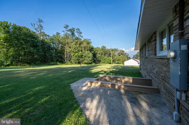 a view of a house with a big yard and large trees