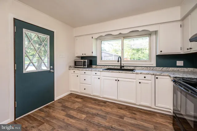 a kitchen with granite countertop a stove a sink and a microwave