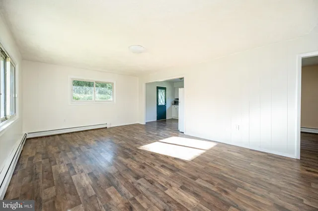 an empty room with wooden floor and windows