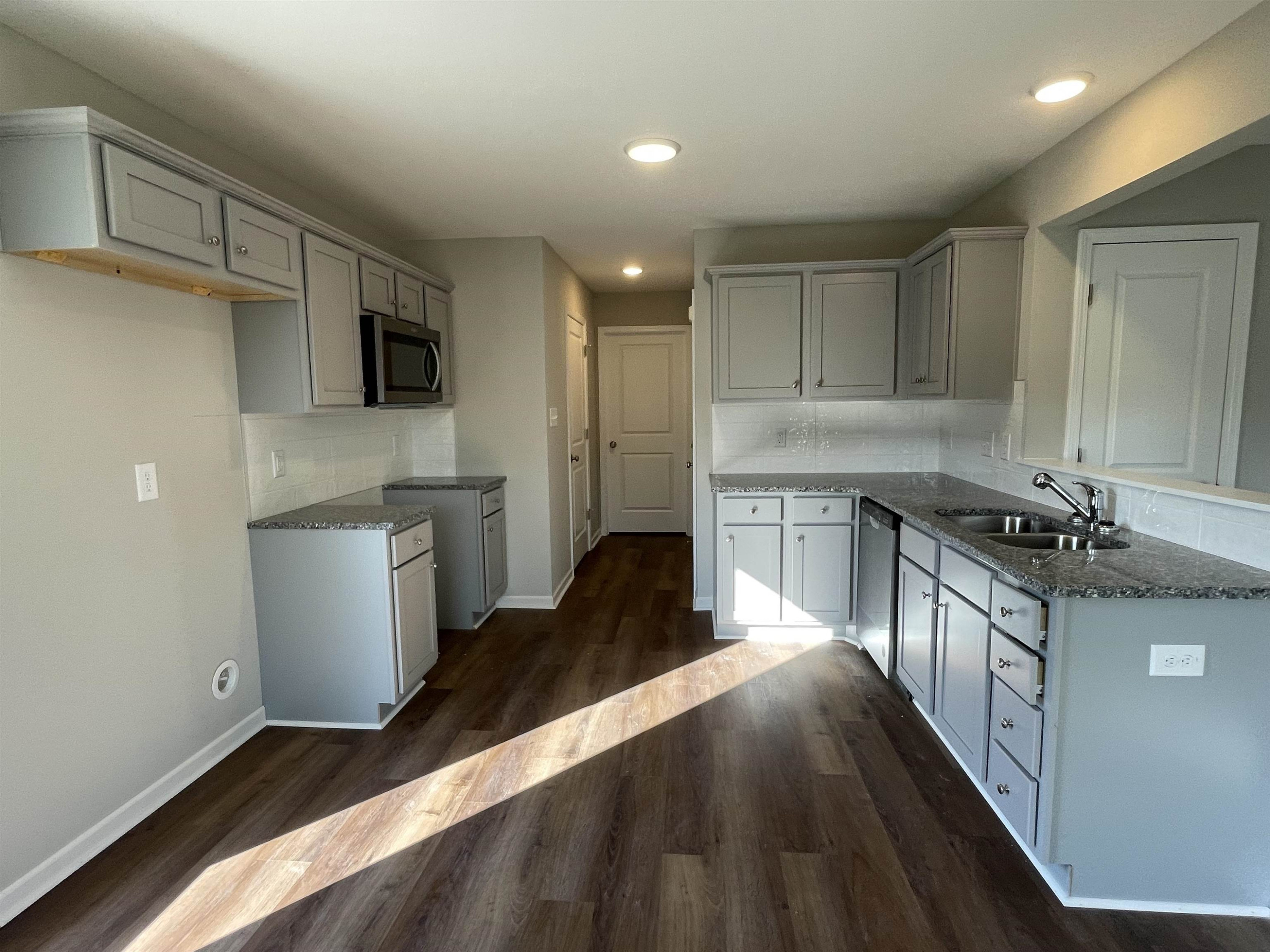 394 Touchdown Way Benson, NC 27504 - Photo 3 of 20 a kitchen with granite countertop a sink a stove top oven and wooden cabinetry