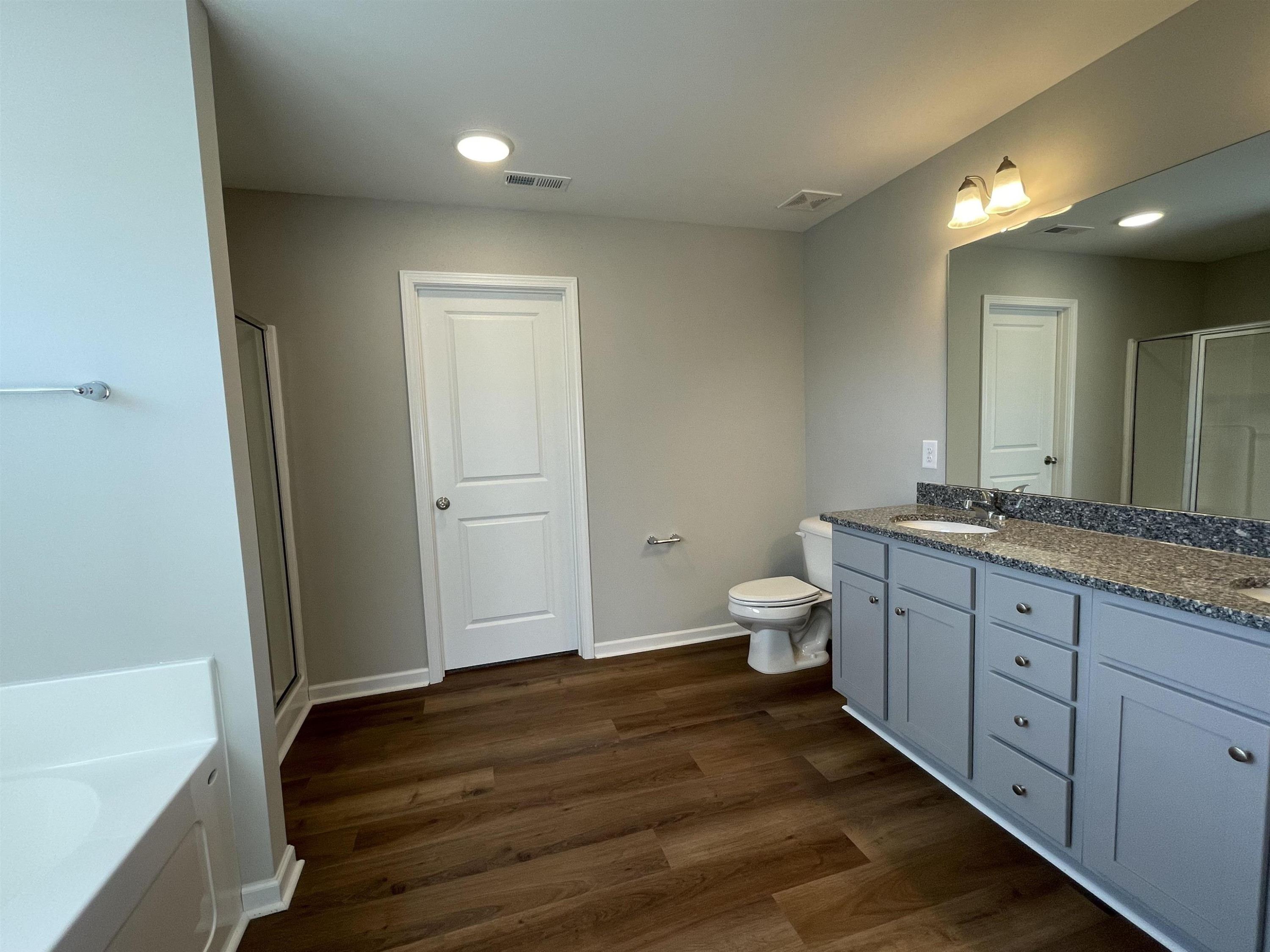 394 Touchdown Way Benson, NC 27504 - Photo 10 of 20 a bathroom with a granite countertop sink a toilet and a bathtub