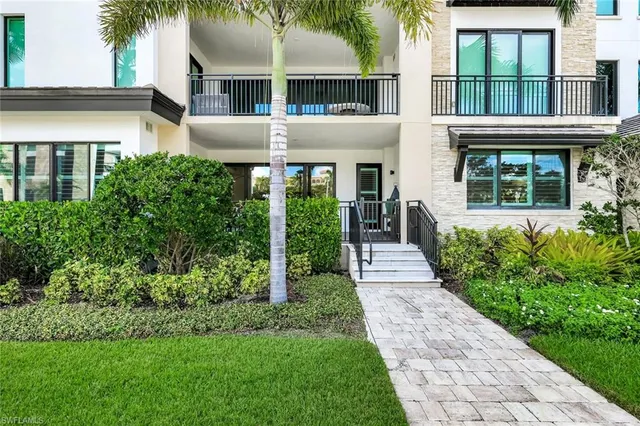 a front view of a house with a yard and potted plants