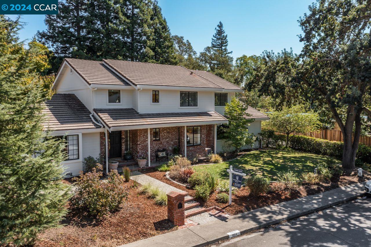 a view of a white house next to a yard with plants and trees
