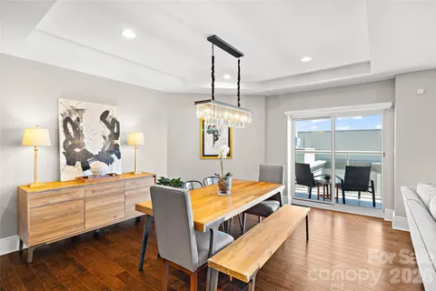 a dining room with wooden floor a chandelier a wooden table and chairs