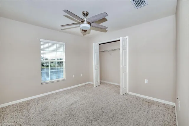 an empty room with windows and fan