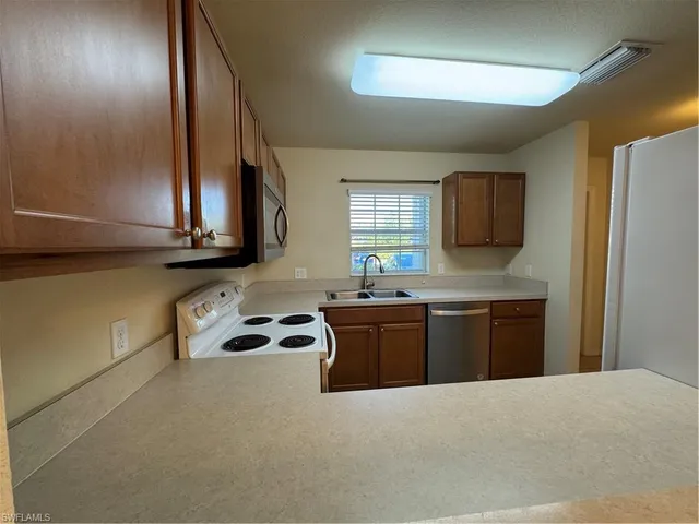 a kitchen with granite countertop a sink stove and refrigerator