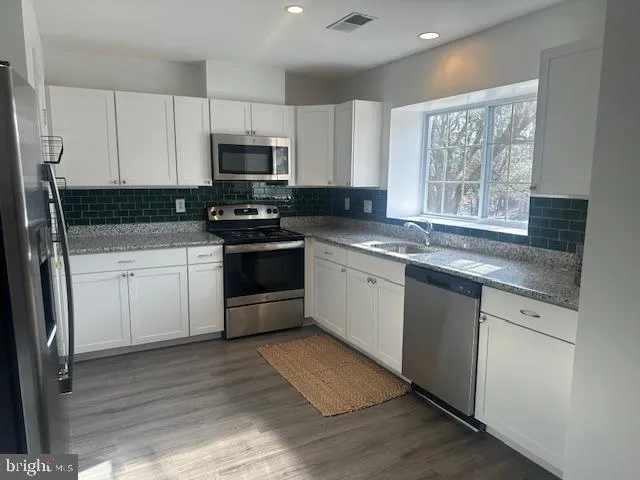 a kitchen with stainless steel appliances granite countertop a stove a sink and a microwave