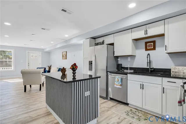 a kitchen with stainless steel appliances kitchen island sink refrigerator and cabinets