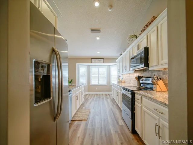 a large kitchen with stainless steel appliances lots of counter space and wooden floor