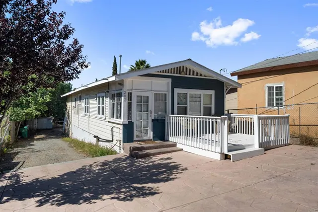 a view of a house with a small yard and wooden fence