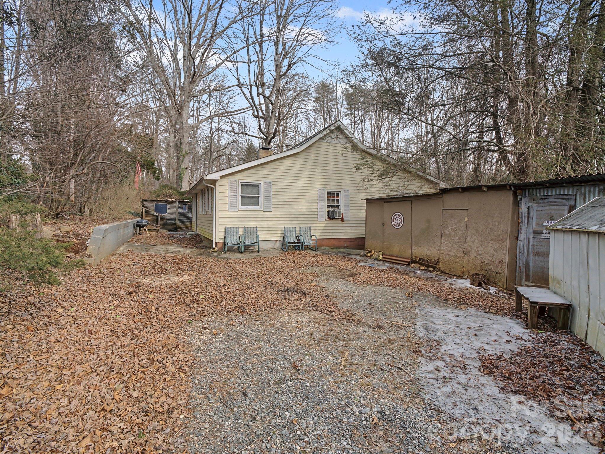1526 Bills Creek Road Lake Lure, NC 28746 - Photo 2 of 25 a backyard of a house with large trees and wooden fence
