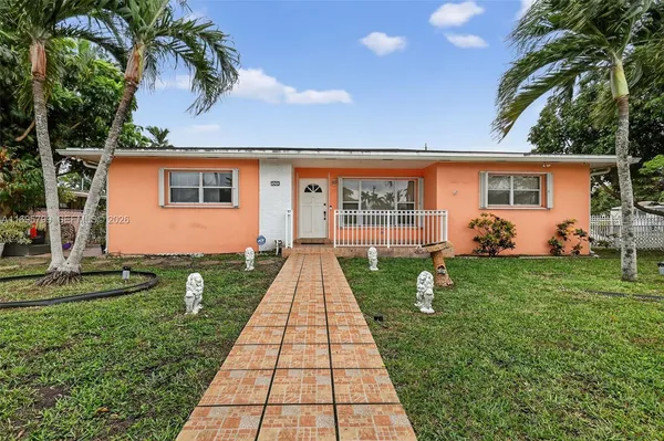 a backyard of a house with potted plants and palm trees