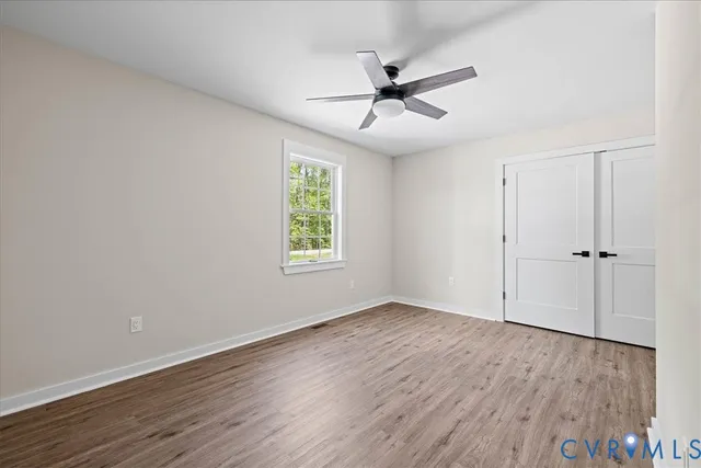 an empty room with wooden floor fan and windows