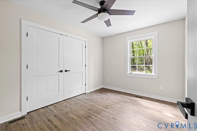 a view of an empty room with a window and wooden floor