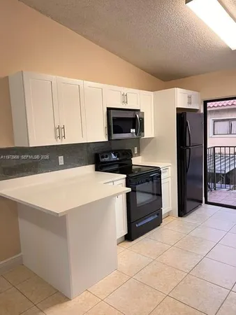 a kitchen with granite countertop a refrigerator and a stove top oven